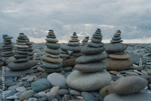 Sticker Stone stacks on a pebble beach under cloudy sky