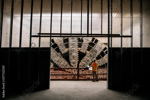 A construction white worker inspects a large tunnel boring machine