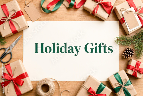 Holiday gifts surrounded by wrapping paper, ribbons, scissors, twine, and pine decorations. Christmans concept background