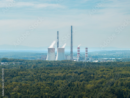 Canvas Print Power plant releasing steam and smoke into atmosphere above green forest