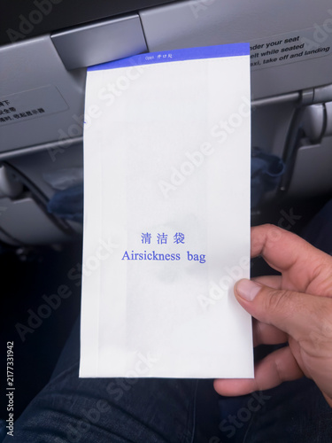 Foto Hand holding an airsickness bag on an airplane