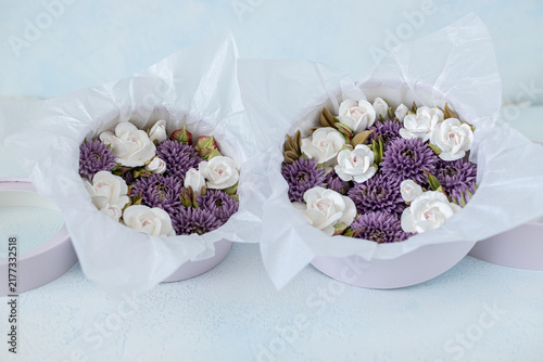 Floristry from Zephyr. Floral arrangement in round purple boxes featuring white roses and purple asters, elegantly presented with tissue paper on a light background