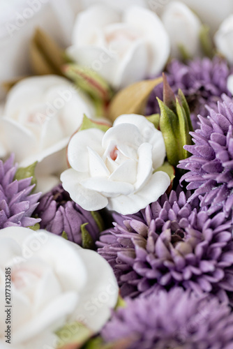 Floristry from Zephyr. White and purple artificial flowers arranged together in a decorative display, showcasing intricate details and textures of petals and leaves
