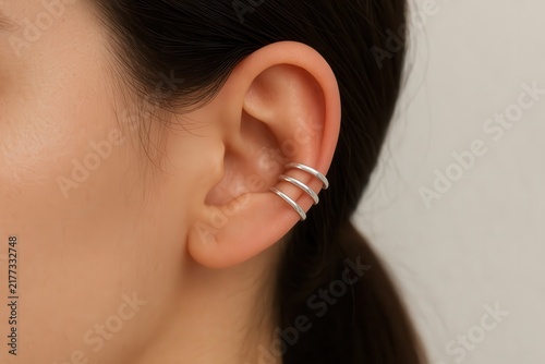 Minimalist silver ear cuffs on adult's ear close-up