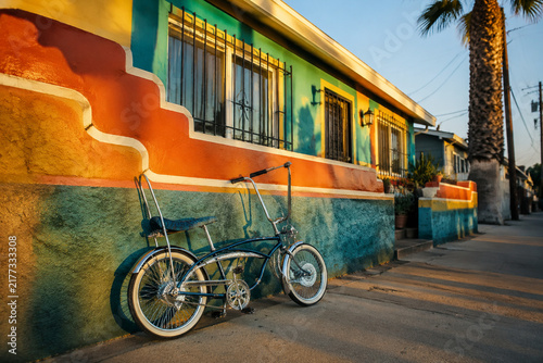 A lowrider bicycle leaning against a colorful stucco wall.