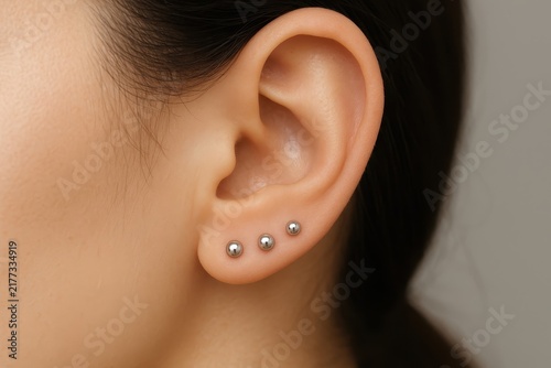 Close-up of woman's ear with triple lobe piercings