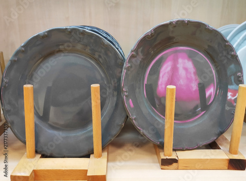 Plates with colorful decorative patterns on a wooden rack. Stylish ceramic tableware for table setting and home interior design