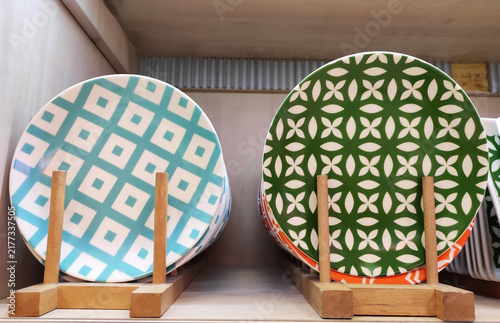 Plates with colorful decorative patterns on a wooden rack. Stylish ceramic tableware for table setting and home interior design