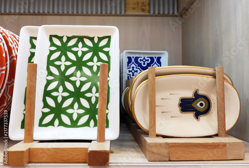 Plates with colorful decorative patterns on a wooden rack. Stylish ceramic tableware for table setting and home interior design