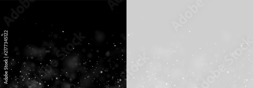 Tiny luminous particles scatter across a black background creating a sparkling bokeh effect. The white dots vary in size and intensity with a soft blurred glow.