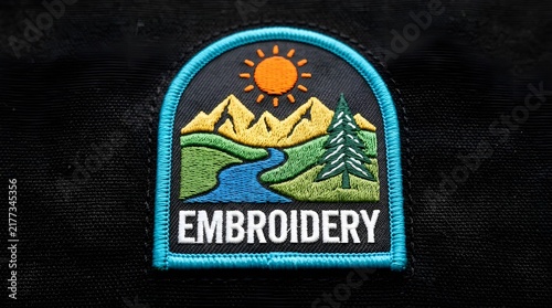 Embroidered badge patch with a colorful mountain landscape scene featuring a sun river and pine tree on a dark background