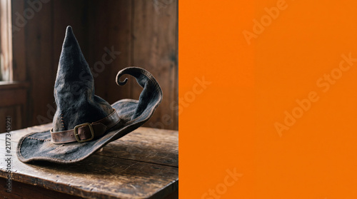 Witch Hat Floating with Curling Brim, Halloween Object on Solid Orange Background with Copy Space