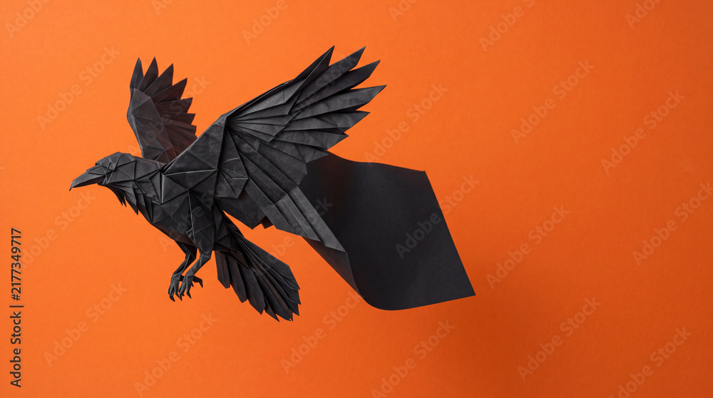 Obraz premium Origami Raven Unfolding Mid Flight, Halloween Paper Craft Object on Solid Orange Background with Copy Space
