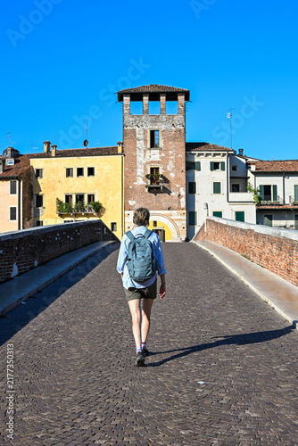 Woman walking across historic bridge in Verona, Italy