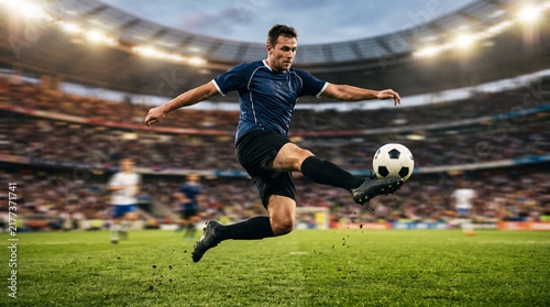 Soccer player kicking ball in packed stadium during professional football match