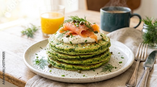 Spinach pancakes topped with smoked salmon and herbs on a plate  