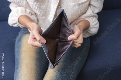 Obraz na płótnie Woman showing an empty wallet with no money at home, representing financial hardship, cash shortage, personal debt, budget problems, rising expenses, poverty, cost of living crisis
