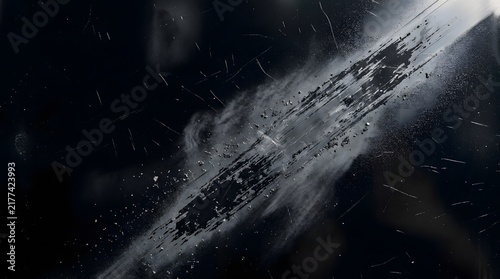 Abstract macro photography showing dark graphite dust and abrasion particles floating in a bright beam of light against black background