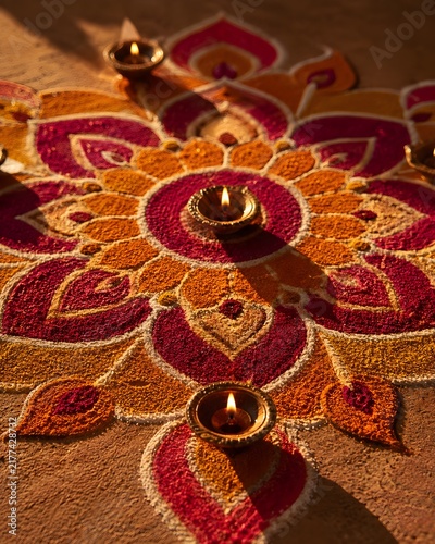 An intricate rangoli pattern in coloured powder, shot from directly above, photo, deep saffron, magenta and gold