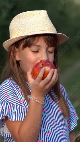 Blue-Eyed 12-Year-Old Girl Smiling While Eating a Fresh Apple. Happy child enjoying fresh fruit from a family orchard during the autumn harvest.