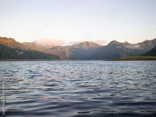 Calming lake reflects distant mountains at dawn