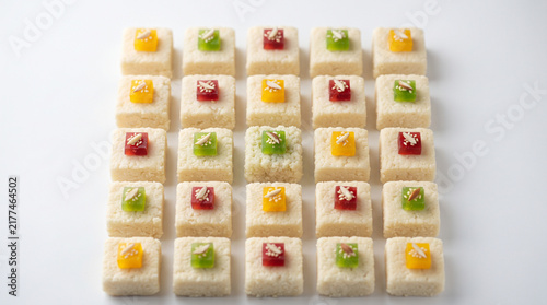 playful mini fruit-topped square pastries in a uniform grid, close up photo with bright contrasting colors and smooth glossy