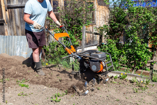 Gardener using motorized cultivator on the plantation. Plowing garden with a motor cultivator before planting potatoes and other crops