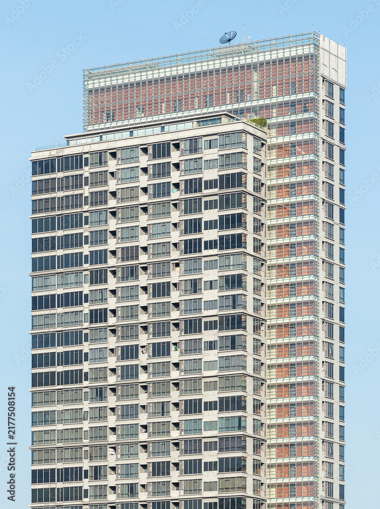 Fototapeta premium Bottom up view green condominium building with blue sky background