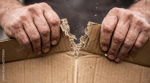 material manipulation, close-up of hands aggressively ripping brown corrugated cardboard apart