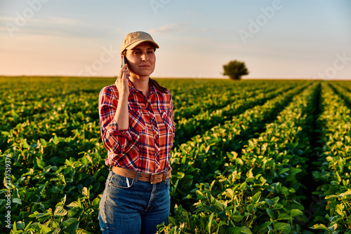 Konstfotografi Female farmer talking on smartphone in an agricultural soybean field, managing f