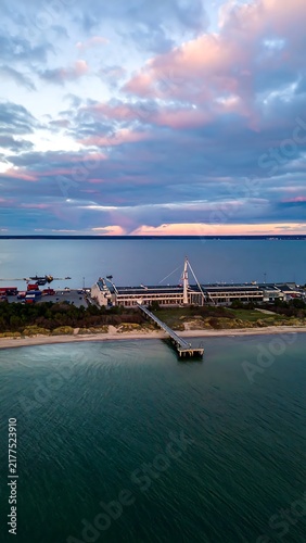 Sunset over tranquil coastal pier with boats.