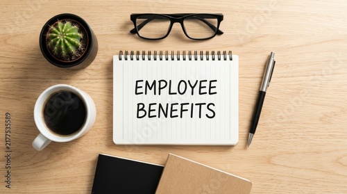 Employee benefits concept with notebooks, glasses, and coffee on a wooden table.