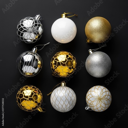 A collection of elegant shiny gold, silver, and white Christmas ornaments resting on a dark black background for festive holiday decor, celebration, winter, gold