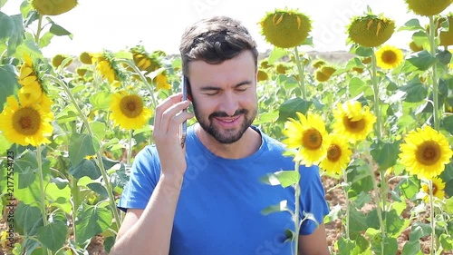 Video of a young gorgeous natural man making a phone call from a sunflowers field