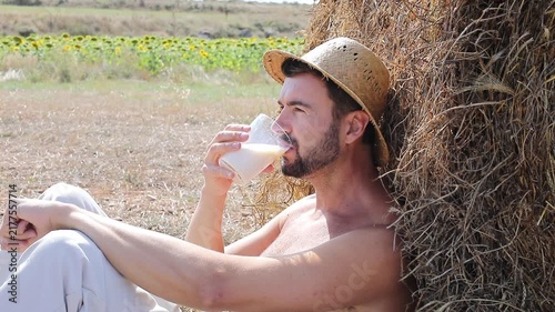 Attractive Shirtless Farmer Drinking Fresh Milk in Sunflower Field