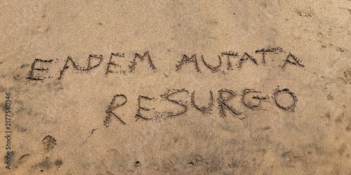 Hand written beach sand. Eadem mutata resurgo  is a Latin phrase that translates to Although changed, I arise the same.