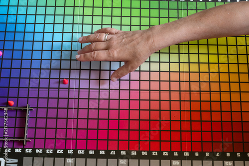 Hand reaching across colorful board game with grid and game pieces