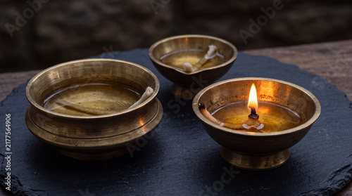 Close up of traditional brass diya oil lamps with glowing flames on a dark surface, symbolizing Diwali festival and spiritual light.