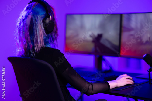 Canvastavla Young gamer immersed in virtual world with dual screen setup and colorful lighti