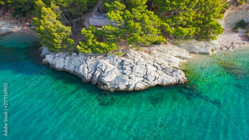Drone view of an Adriatic coastal town with turquoise sea, green hills and a beach.