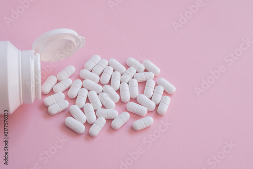 Foto White tabletts or pills on the pink background with place for text