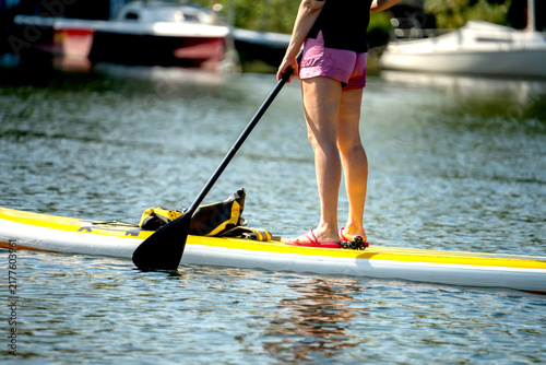 Photography Woman stands on yellow paddleboard, paddling calmly
