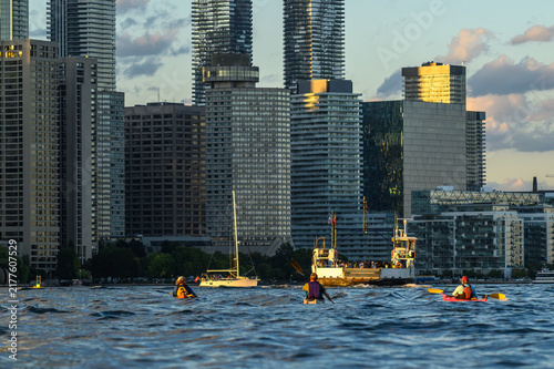 Canvas Print Sea kayakers paddle across Toronto's Inner Harbour past a sailboat and ferry wit