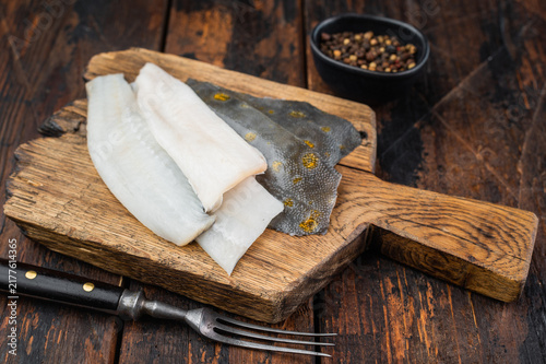 Konstfotografi Raw flounder flatfish fillets with skin on rustic wooden board with fork and pep