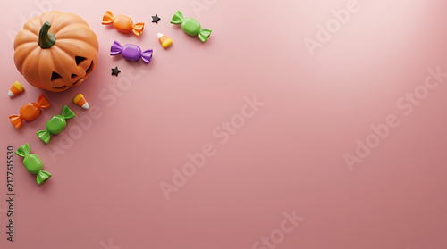 Small carved pumpkin with colorful candy treats arranged on a soft pink surface for a fun Halloween celebration background