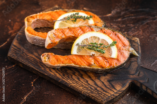Cuadro en lienzo Barbecue style cooked salmon steaks with skin on wooden board with herbs lemon a