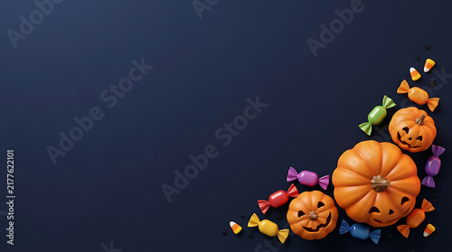 Halloween background with pumpkins and colorful candies arranged in a corner on a dark blue surface
