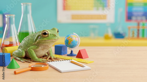Curious green frog sits among colorful classroom supplies and science equipment, creating a playful educational back-to-school learning concept.