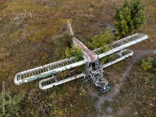 Decayed AN-2 airplane in overgrown airfield, look down drone view