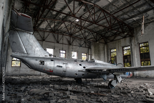 Vintage military trainer jet aircraft plane left to decay in empty hangar, eastern european aviation history